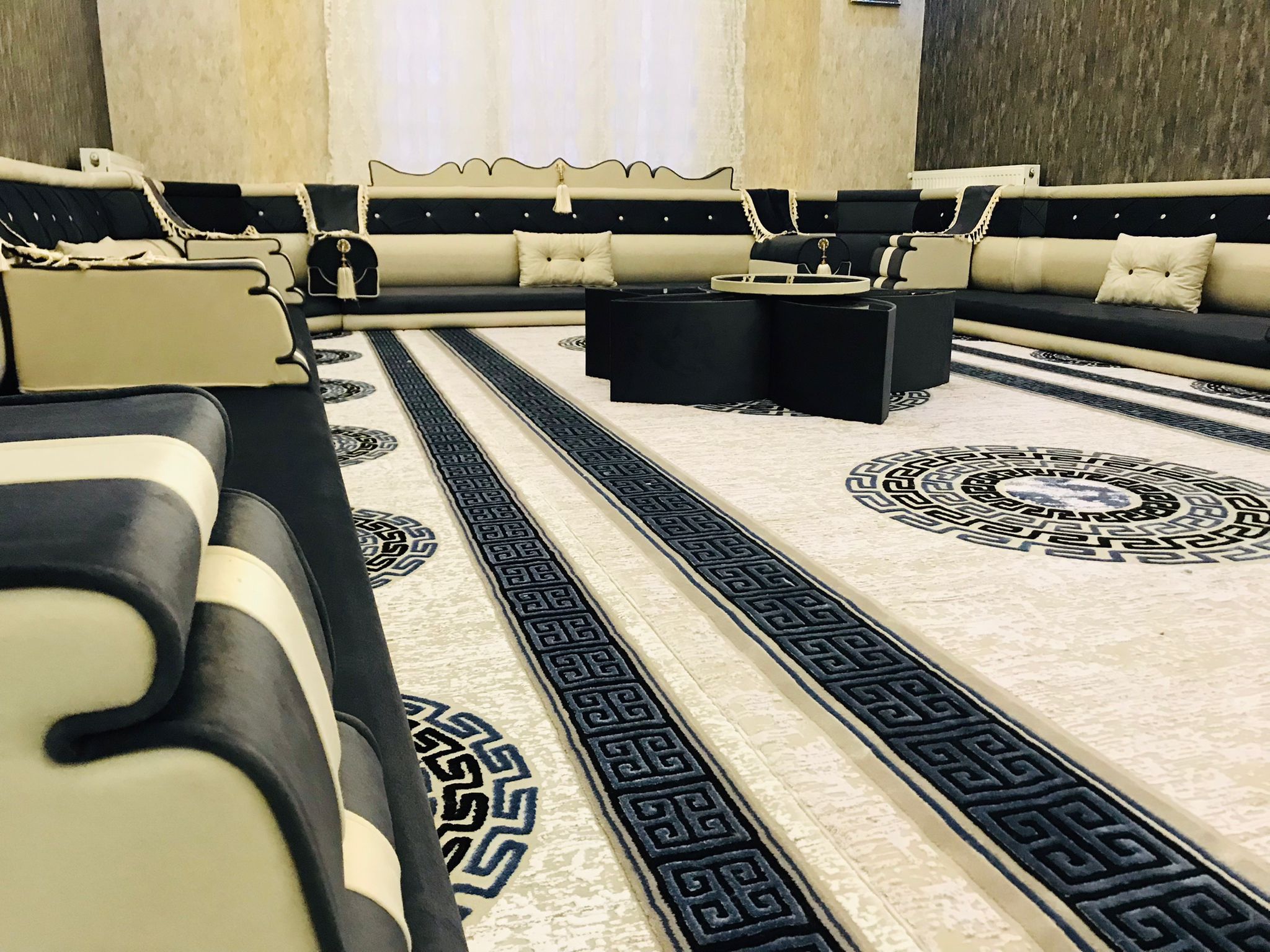 IMG-20210616-WA0046-1 Diwanzane’s modern Arabic Majlis seating set with black and beige tones, plush cushions, and intricate rug patterns for an elegant living room.